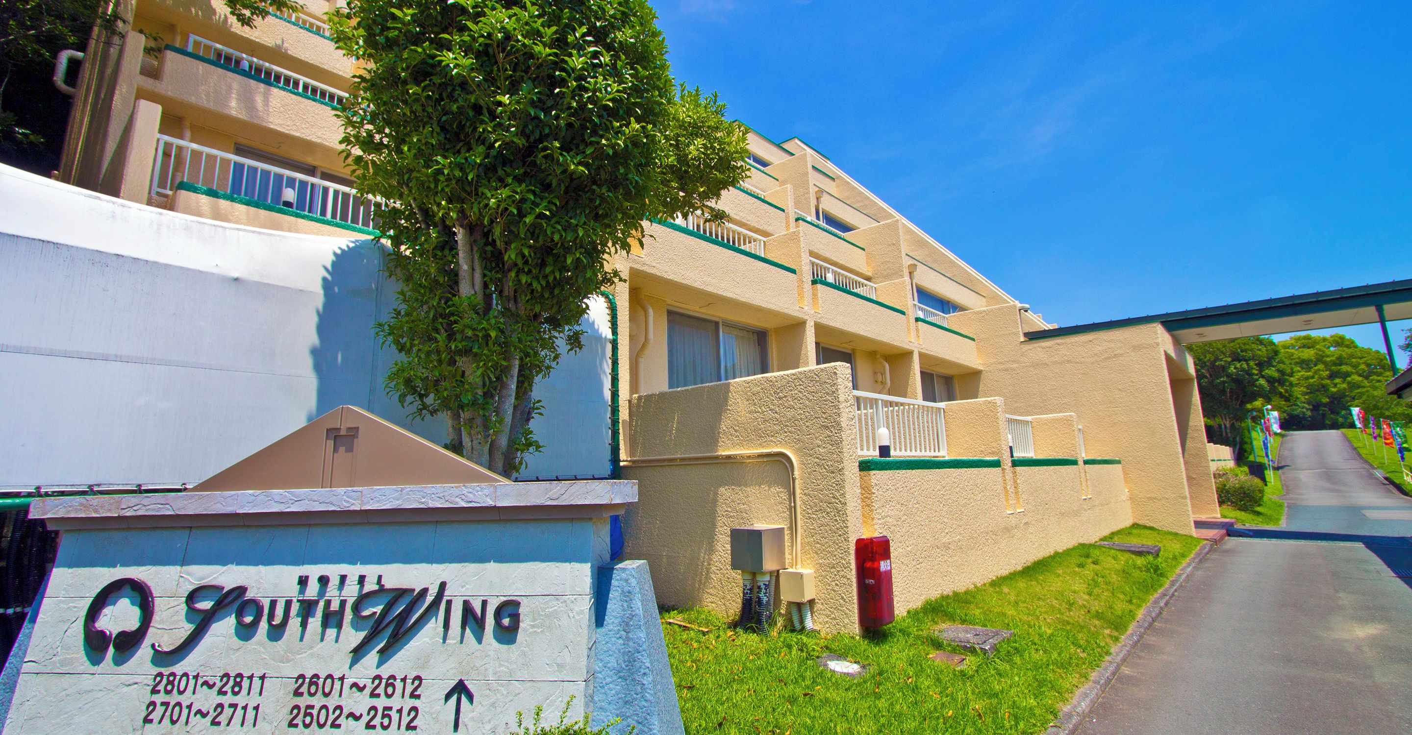 A building with a sign indicating unit numbers and an overpass in the background.