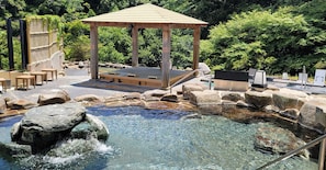 A hot spring area with a wooden gazebo, stone seating, and a small pool. - Tsumagoi Resort Sai No Sato (Kakegawa)