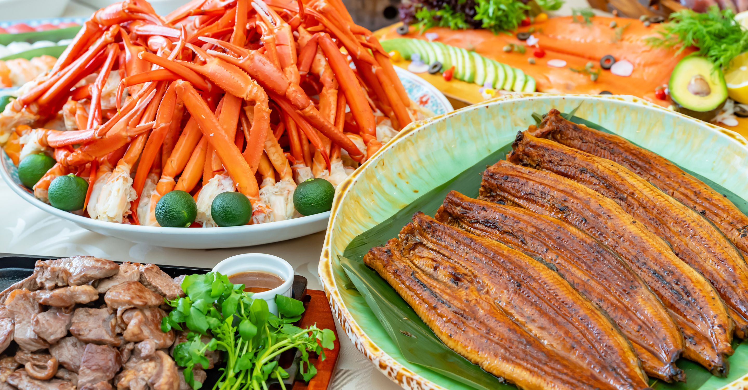 A variety of seafood dishes including crab legs, grilled fish, and a bowl of meat.