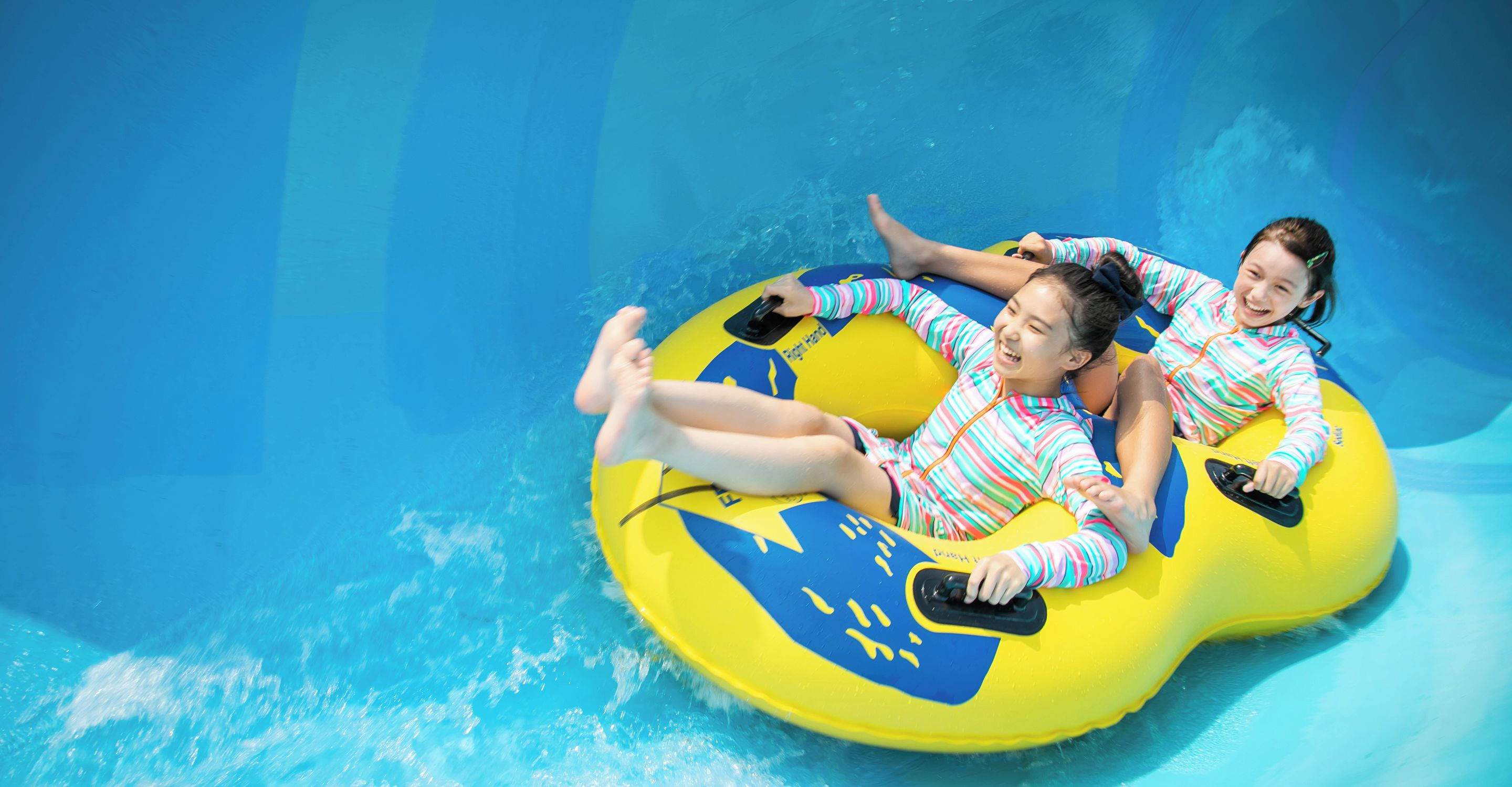 Zwei Personen in einem Pool, die einen gelben und blauen Schwimmreifen benutzen.