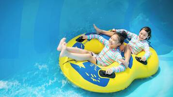 Zwei Personen in einem Pool, die einen gelben und blauen Schwimmreifen benutzen.