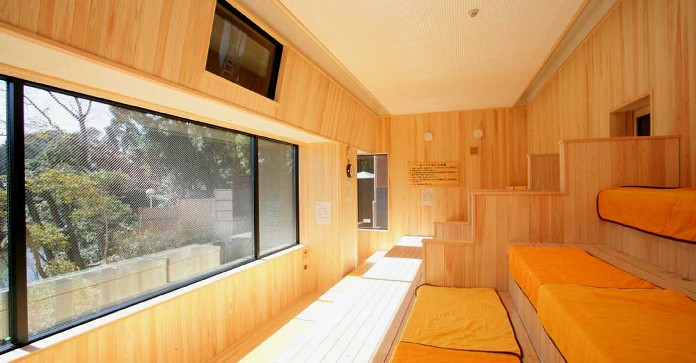 Una habitación con paredes de madera, un ventanal grande y una cama con colchón.