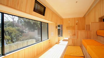 Una habitación con paredes de madera, un ventanal grande y una cama con colchón.