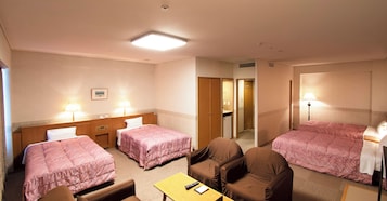 A hotel room with two beds, a desk, a chair, and a bathroom visible through an open door.