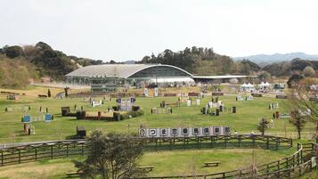 An equestrian event with a large covered arena, multiple jumps, and spectators.