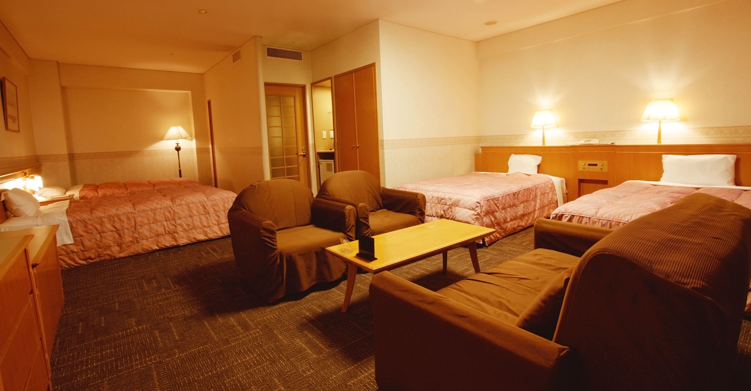 Een hotelkamer met twee eenpersoonsbedden, een bank, een klein tafeltje en een stoel.