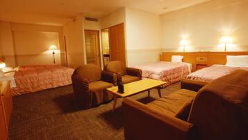 Een hotelkamer met twee eenpersoonsbedden, een bank, een klein tafeltje en een stoel.