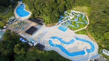 An aerial view of a water park with multiple swimming pools, slides, and a large open area with umbrellas.