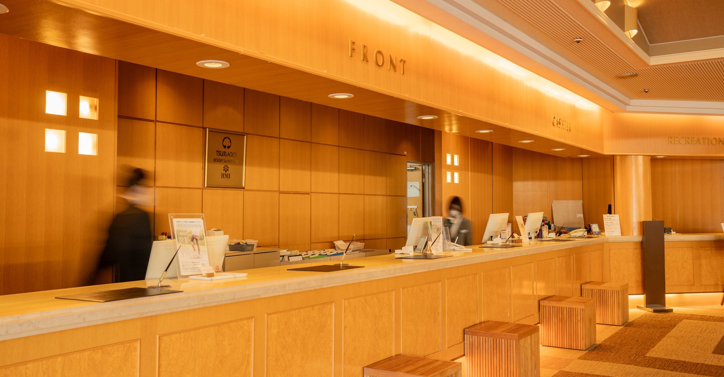 A reception desk with a wooden finish, a framed sign above, and a counter with various items.