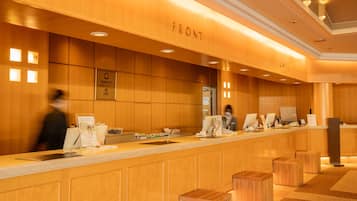 A reception desk with a wooden finish, a framed sign above, and a counter with various items.