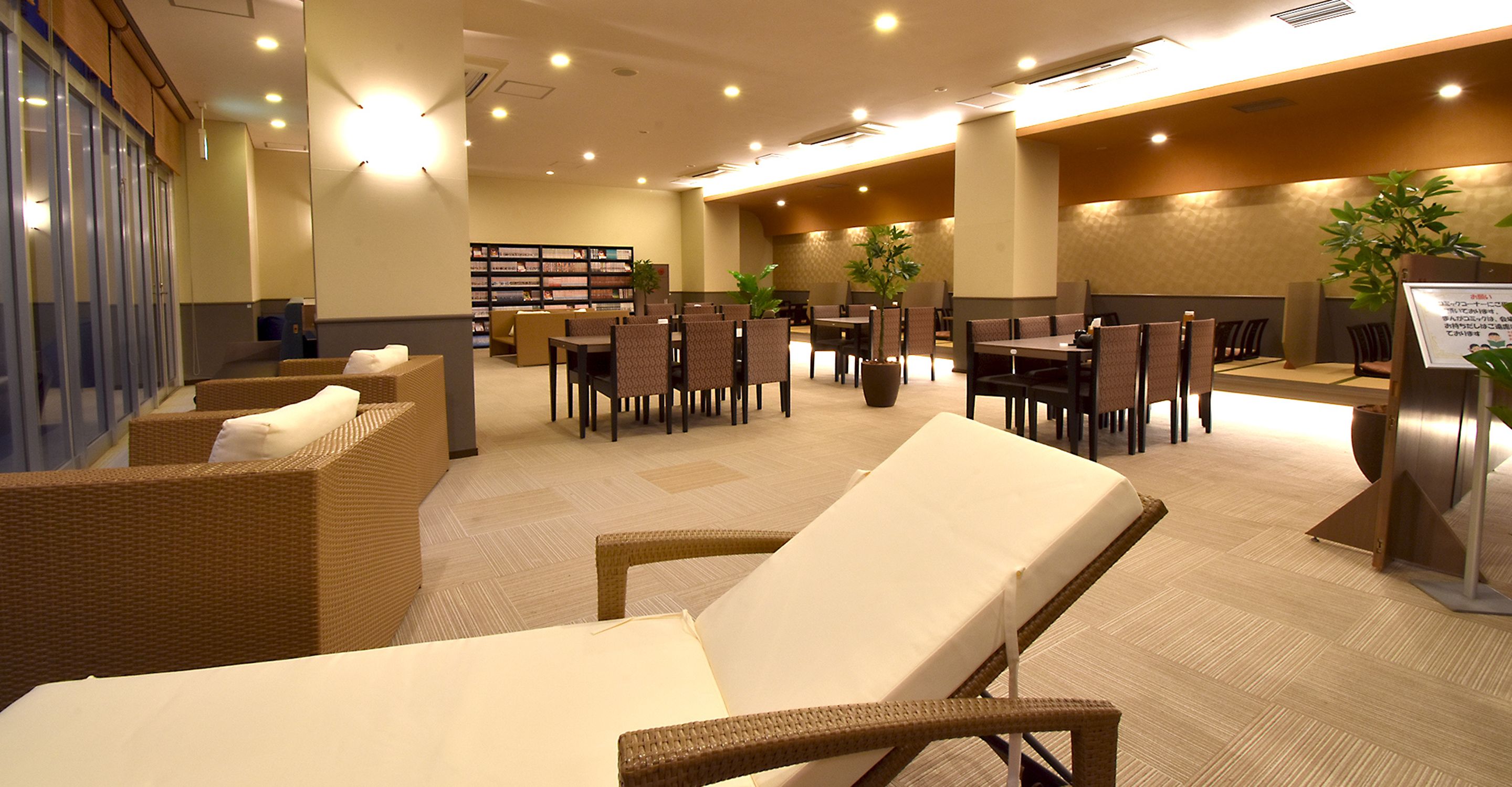 A hotel lobby with seating areas, a reception desk, and a bookshelf.