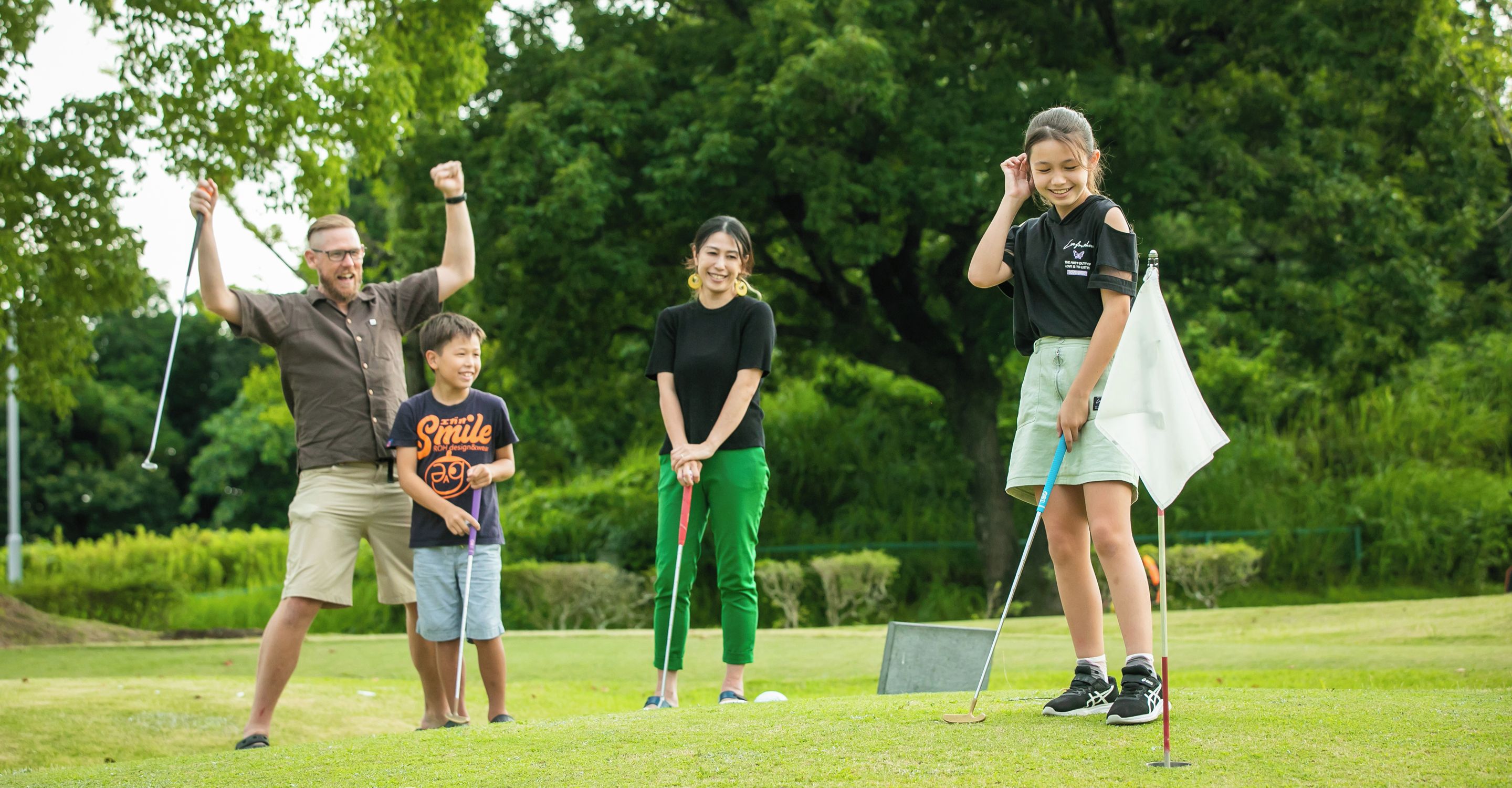 A group of people on a golf course with trees in the background.