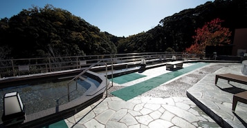 A pool area with a stone deck, a metal railing, and a bench.