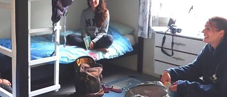 Un dormitorio con literas, escritorio y ventana con cortinas.