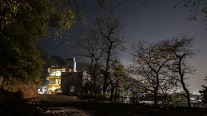 A building with a sign reading "Bunk Stay" and "Bunkpalace Hostel" at night, surrounded by trees and a clear sky. - Riverside home by bunkstay (Yamkeshwar)