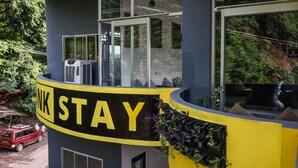 A building with a sign reading "NK STAY" and a red car parked outside. - Riverside home by bunkstay (Yamkeshwar)