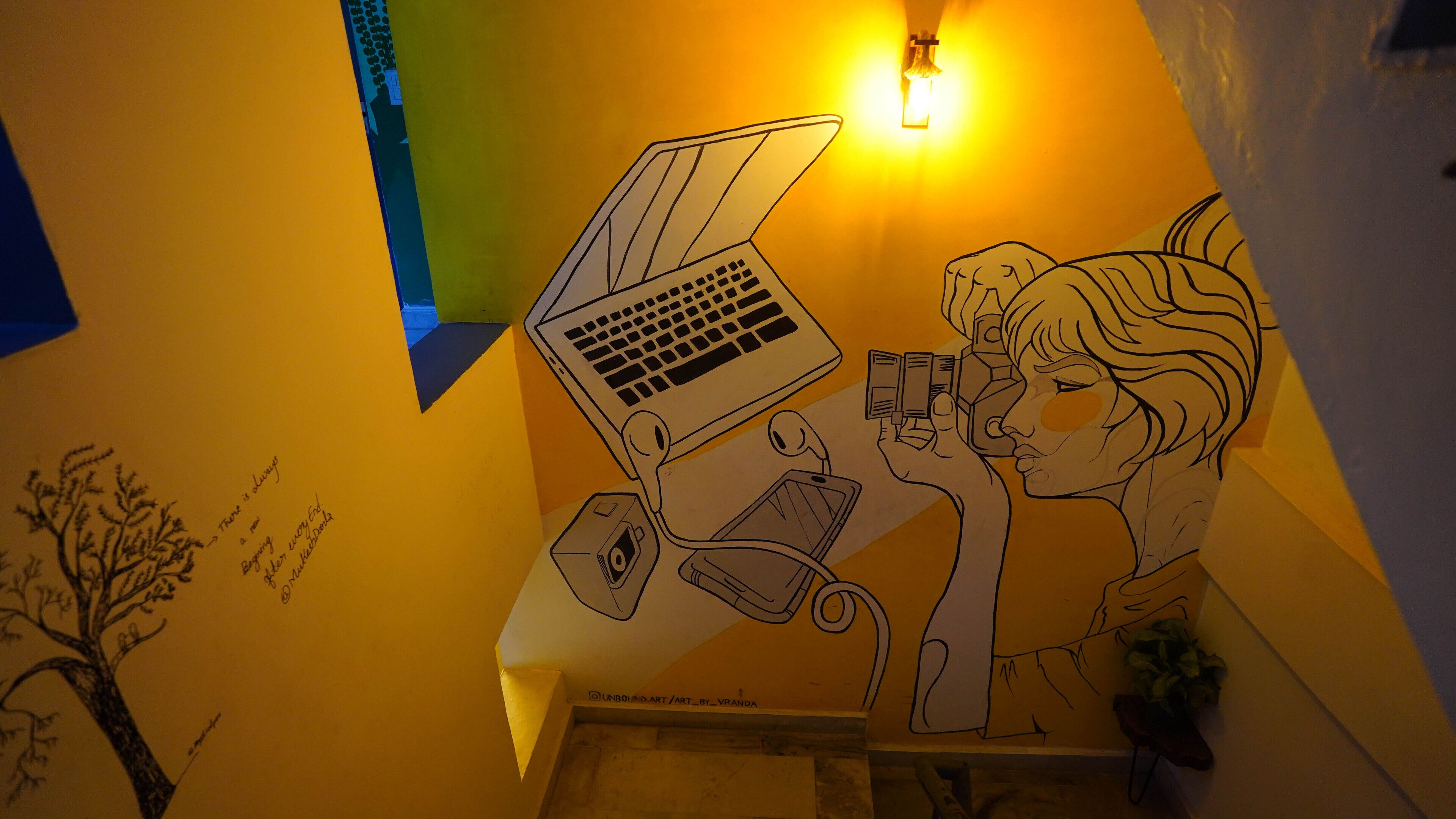 Un mur orné d’une fresque représentant une personne utilisant un ordinateur portable et un téléphone intelligent.