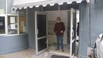 A person standing at the entrance of a building with a white awning, a door, and a window.
