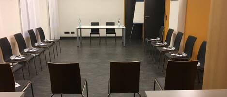 Un salón de conferencias con una larga mesa y sillas, una pizarra y cuadros en las paredes.
