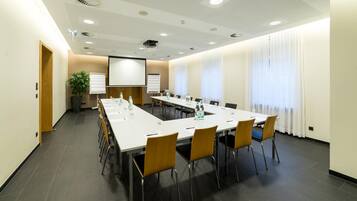 A conference room with a long table, chairs, a projector screen, and a whiteboard.