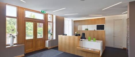 A reception area with a wooden reception desk, a flat-screen TV, and a small seating area.