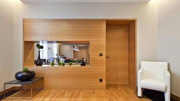 Una habitación moderna con un panel de madera decorativo, una silla blanca y una pequeña mesa con un florero.