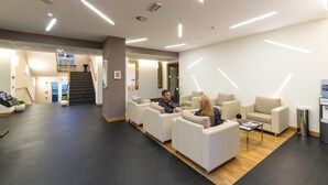 Un área de recepción moderna con una escalera, zona de estar y dispensador de agua.
