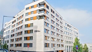 A modern multi-story building with a flat facade, numerous windows, and a sign indicating it is a residence. - Rezidence Muzeum (Prague)