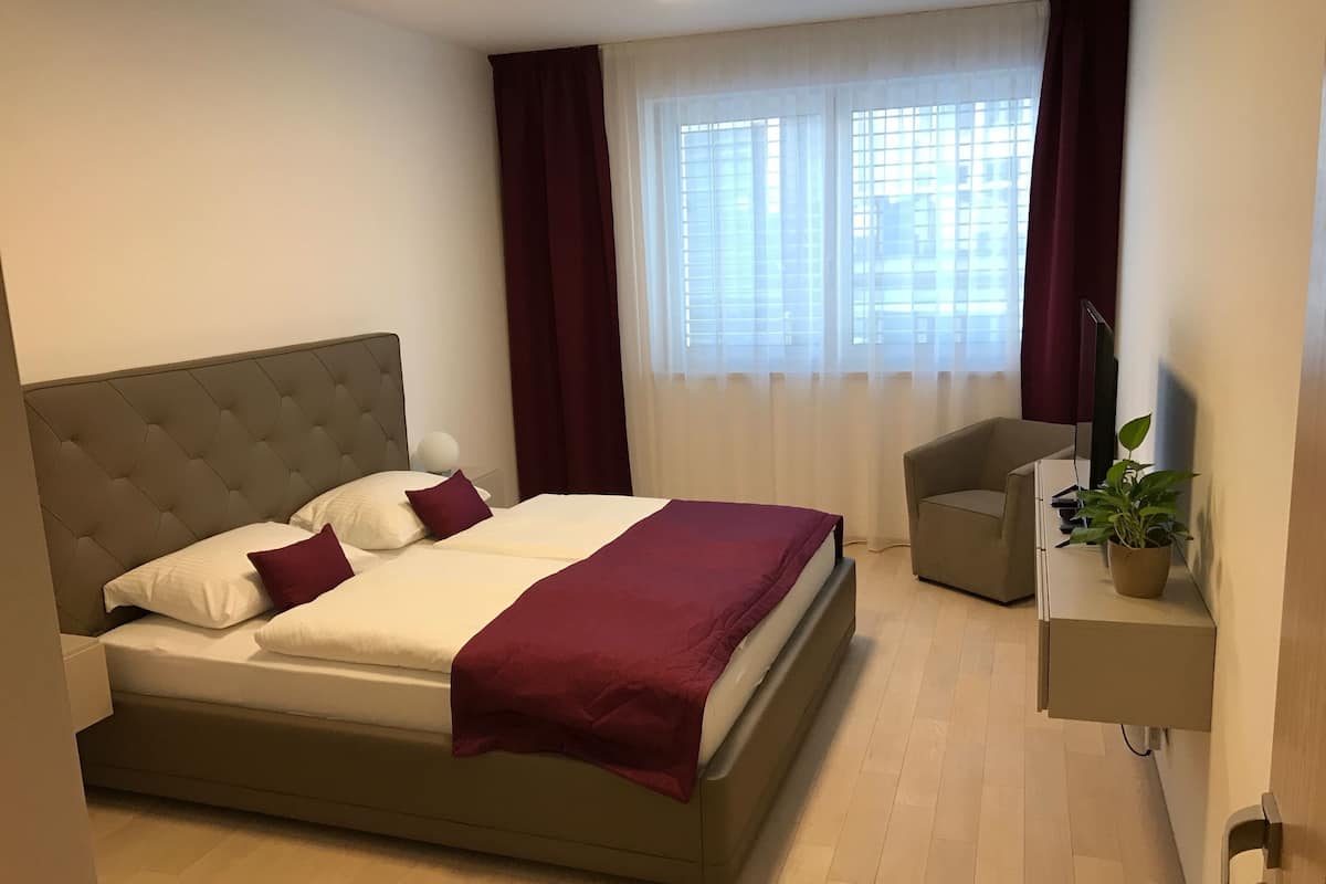 Una camera da letto moderna con un letto grande, una scrivania, una sedia e una pianta in vaso.