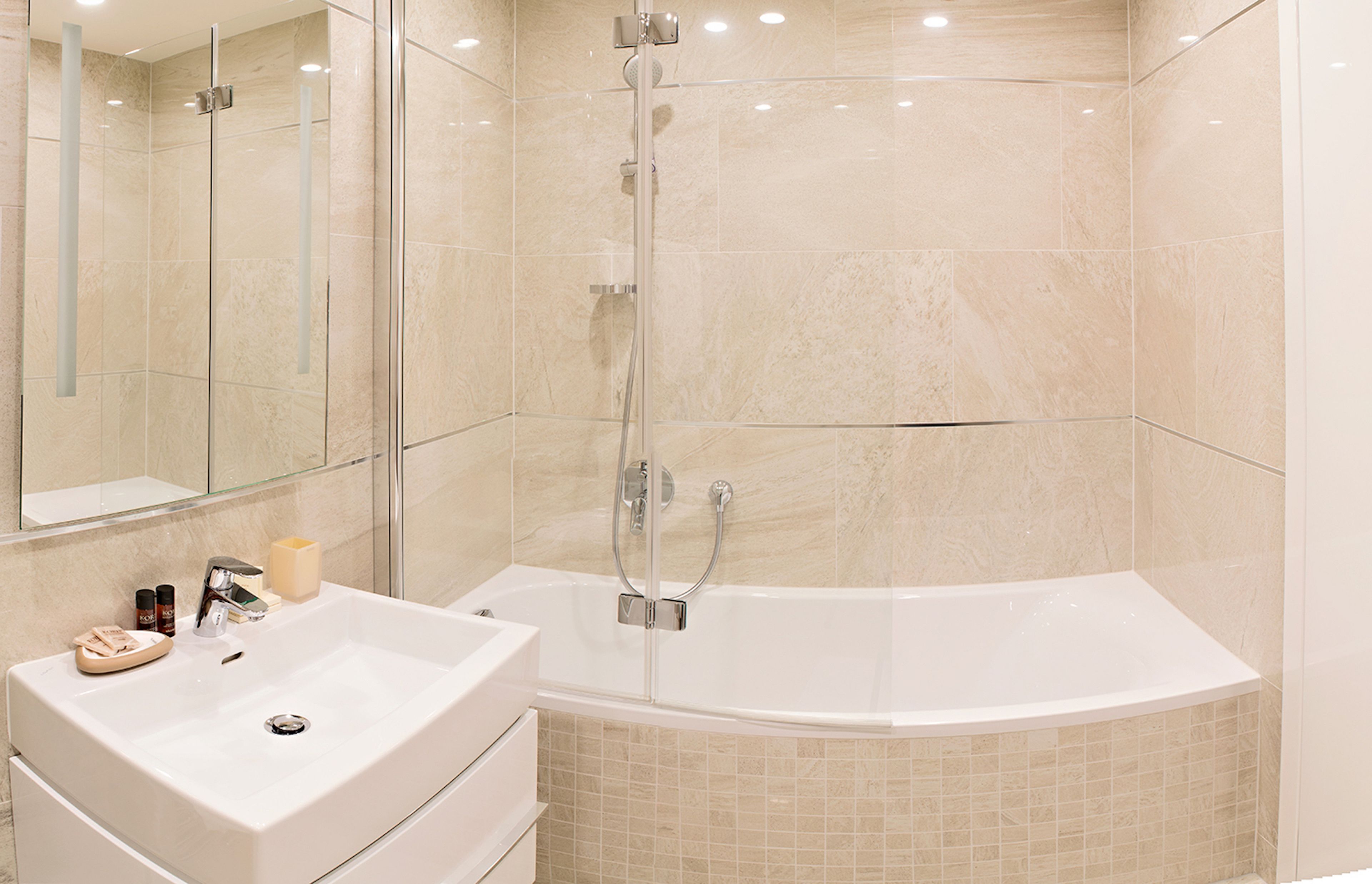 A modern bathroom with a glass-enclosed shower, a freestanding bathtub, and a vanity with a sink and mirror.