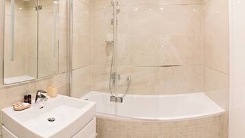 A modern bathroom with a glass-enclosed shower, a freestanding bathtub, and a vanity with a sink and mirror.