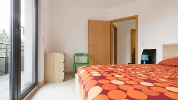 Un dormitorio con cama, una silla, una mesita y un armario.