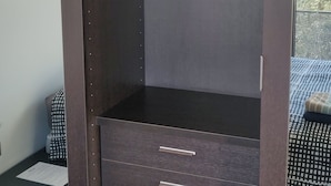 A walk-in closet with a dark wood finish, multiple drawers, and a hanging rod with clothes. - Rooftop Luxembourg Ville (Luxembourg City)