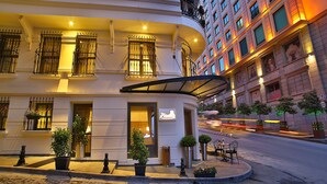 A hotel with a curved entrance, potted plants, and a sign indicating a 30 km/h speed limit. - Adelmar Hotel İstanbul Sisli (Istanbul)