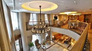 A hotel lobby with a grand chandelier, a balcony with a wrought iron railing, and a seating area with sofas and a coffee table. - Adelmar Hotel İstanbul Sisli (Istanbul)