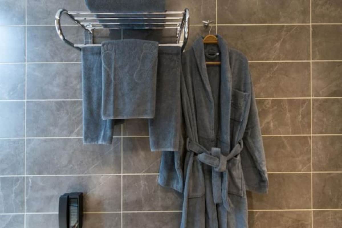 A bathroom with a towel rack holding two towels and a robe hanging on the wall.