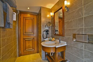 A modern bathroom with a wooden door, a sink with a mirror, and a towel rack. - Adelmar Hotel İstanbul Sisli (Istanbul)