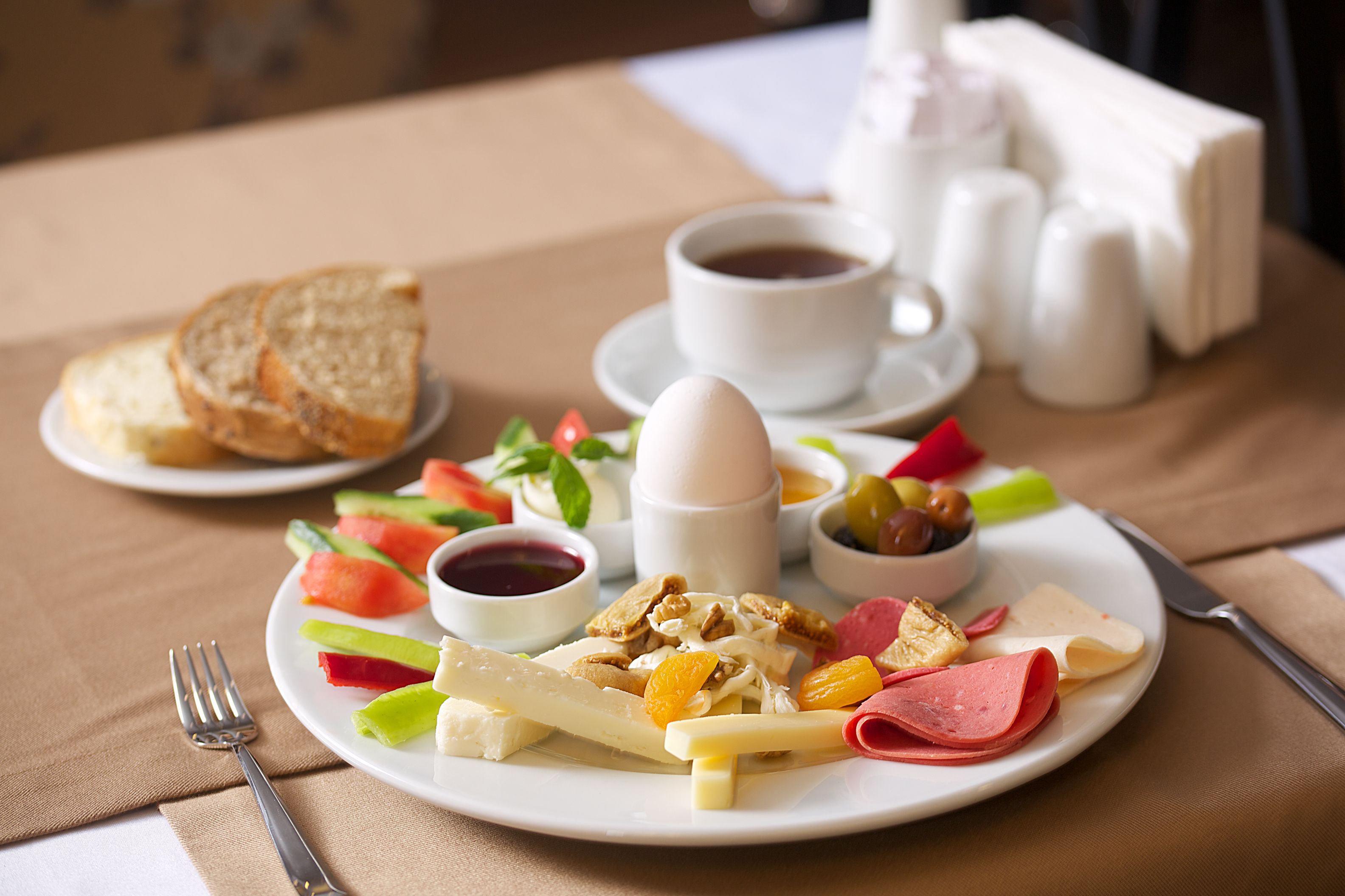 Ein Teller mit Frühstück: Toast, Eier, Käse, Schinken und Obst.