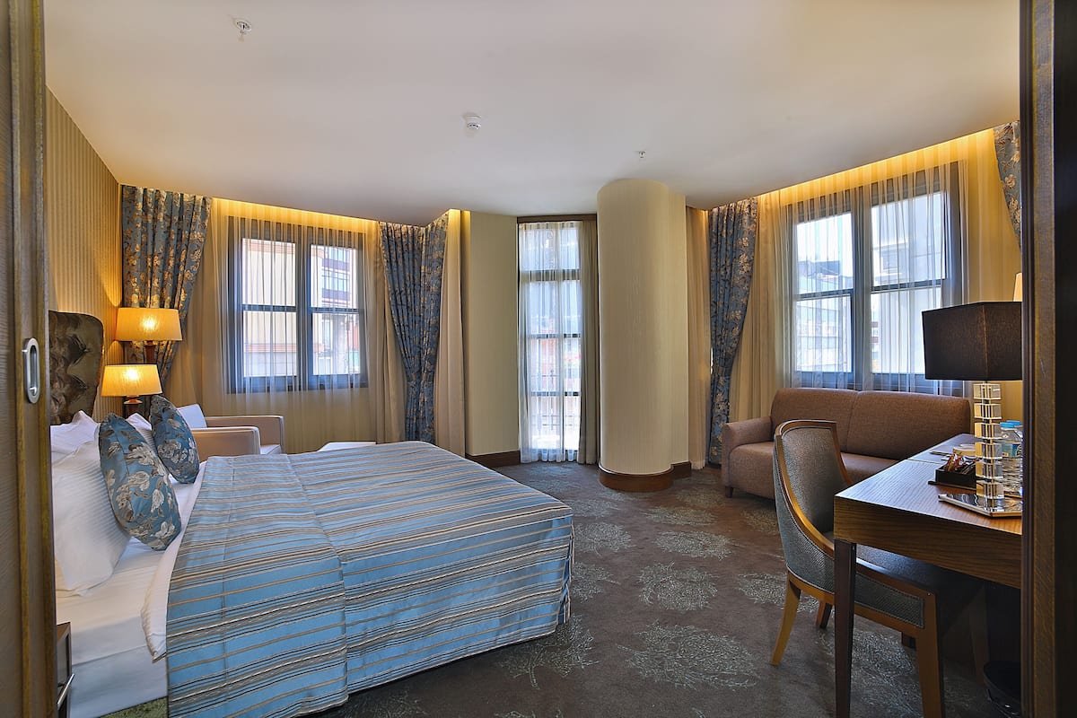 Une chambre d’hôtel avec un grand lit, un canapé, une table à manger et un bureau.