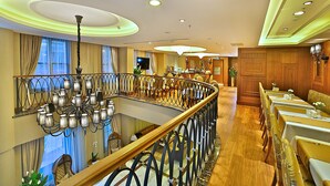 A hotel lobby with a glass railing, a chandelier, and a dining area with tables and chairs. - Adelmar Hotel İstanbul Sisli (Istanbul)
