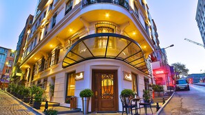 A corner building with a curved balcony, potted plants, and outdoor seating. - Adelmar Hotel İstanbul Sisli (Istanbul)
