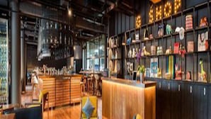 Eine moderne Bar mit Holzboden, einem Empfangstresen und einer Wand mit unterschiedlichen Dekorationselementen.