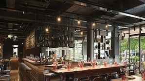 Ein Restaurant mit einer langen Bar, Holztischen und -stühlen.