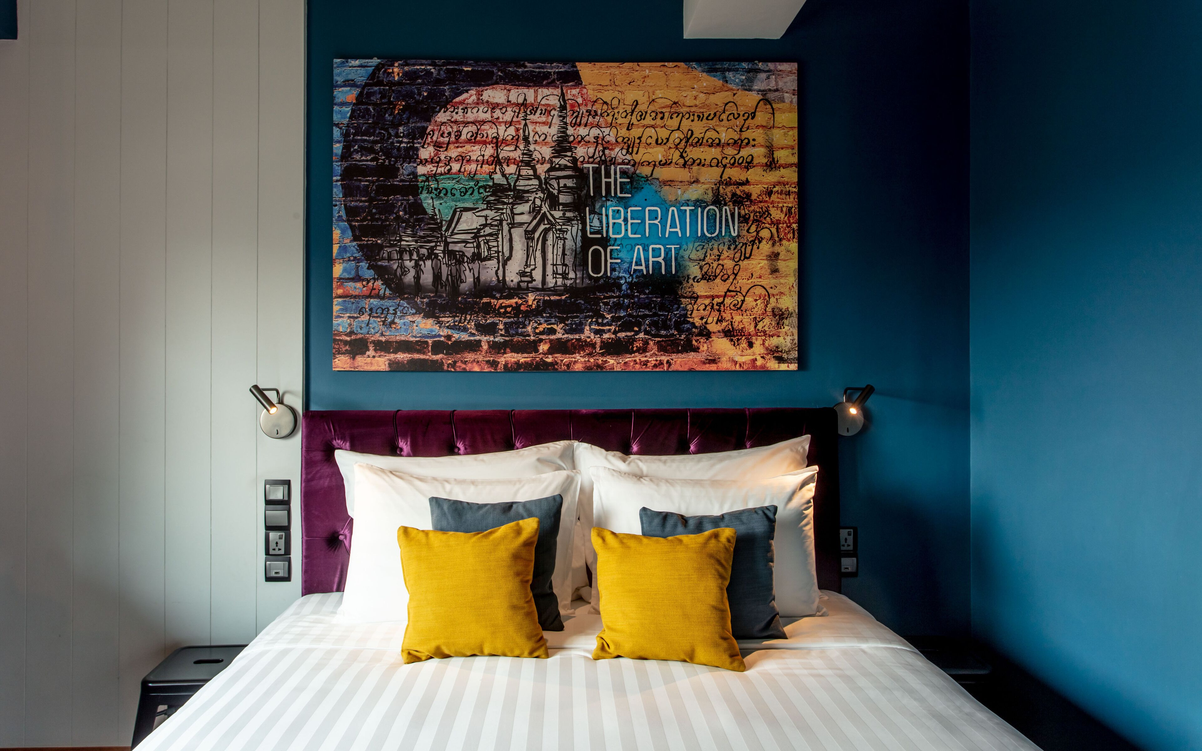 A hotel room with a bed, a headboard, and a wall art piece.