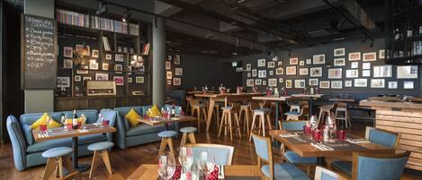 A cozy restaurant with wooden furniture, a chalkboard menu, and framed pictures on the walls.