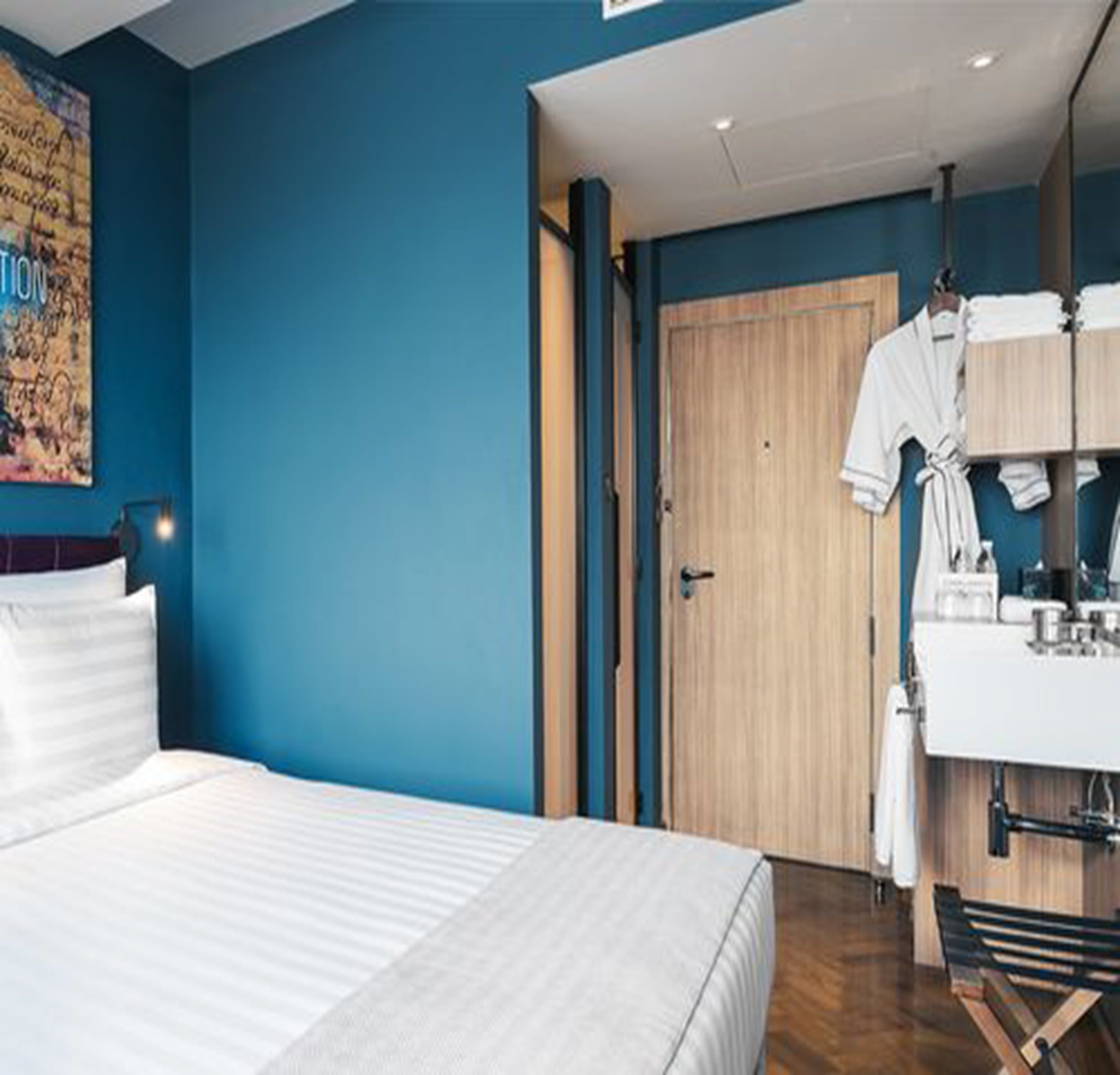 Ein Hotelzimmer mit einem großen Bett, einer Holztür, einem Badezimmer mit Spiegel und einem Handtuchhalter.