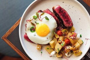 Un plato con bistec, un huevo frito y patatas en cubos.