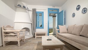 Una habitación con un sofá color beige, una silla de madera, una mesita pequeña y una puerta azul.