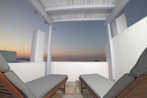 A terrace with two wooden lounge chairs and a white ceiling structure. - Almyra Guesthouses (Skiros)