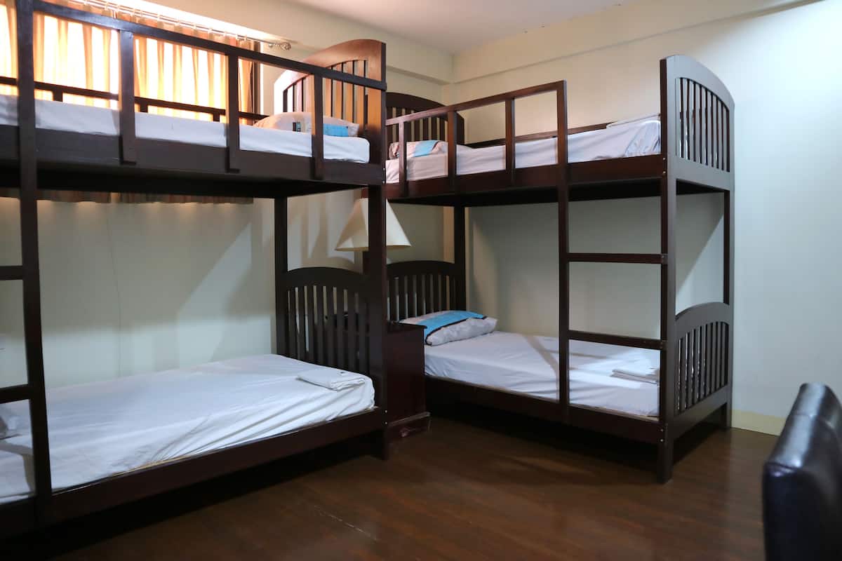 Ein Zimmer mit drei Etagenbetten, Holzboden und einem Stuhl.